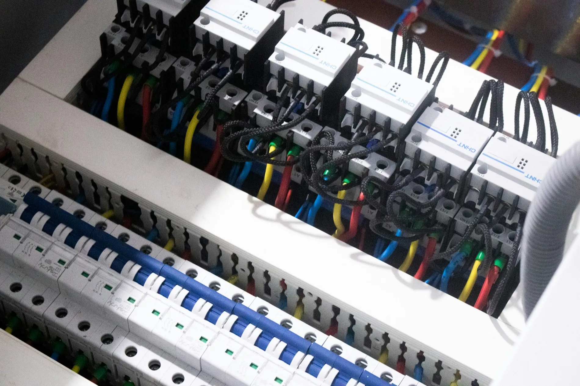 Detail van een verdeelinrichting: installatieautomaten, aardlekschakelaars en gekleurde aansluitdraden.