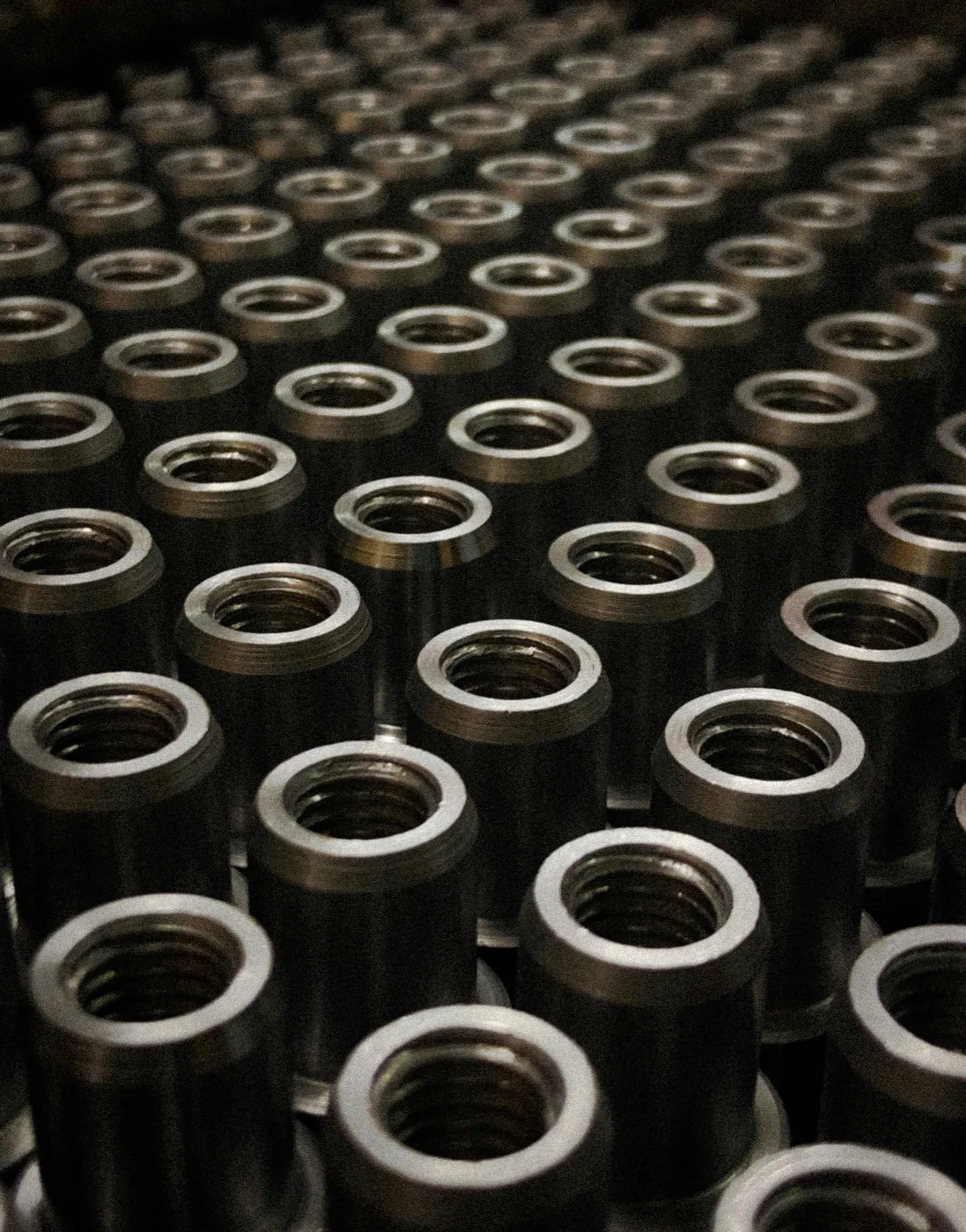 Machined steel rings stacked in rows, still oiled