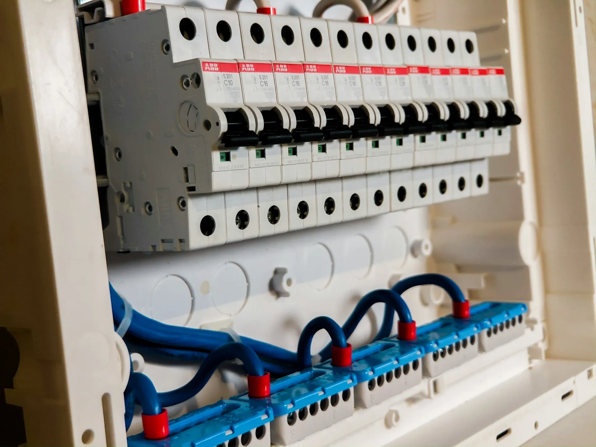 Open groepenkast met een rij installatieautomaten en aangesloten leidingen.