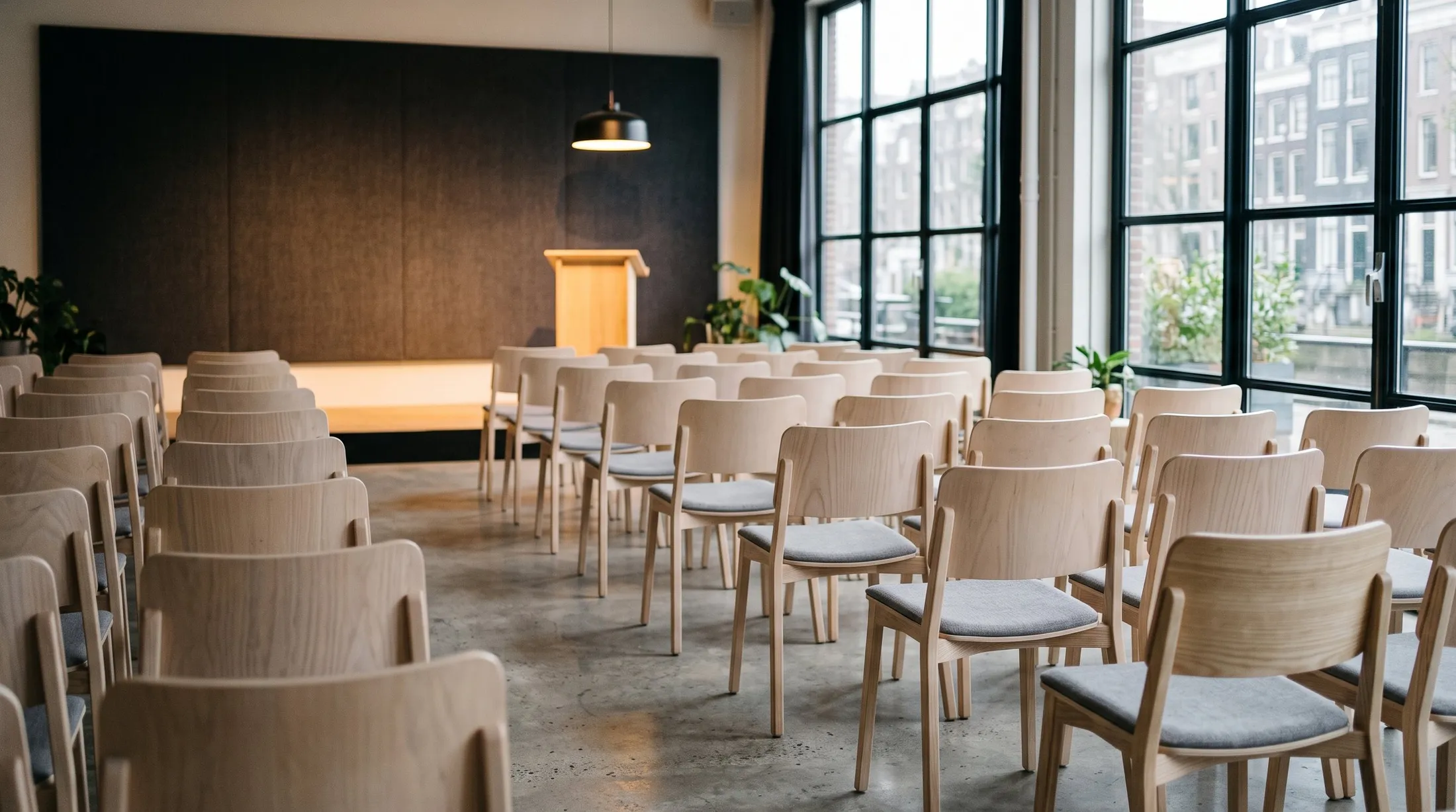 An empty talk venue with pale timber seating angled toward a lit stage