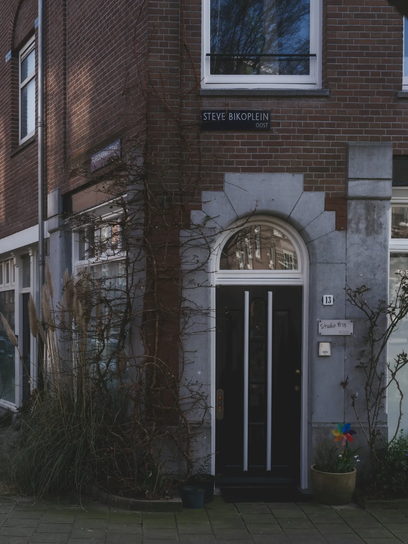Gemetselde entreepartij van een woonblok met een dubbele voordeur onder een bakstenen boog.