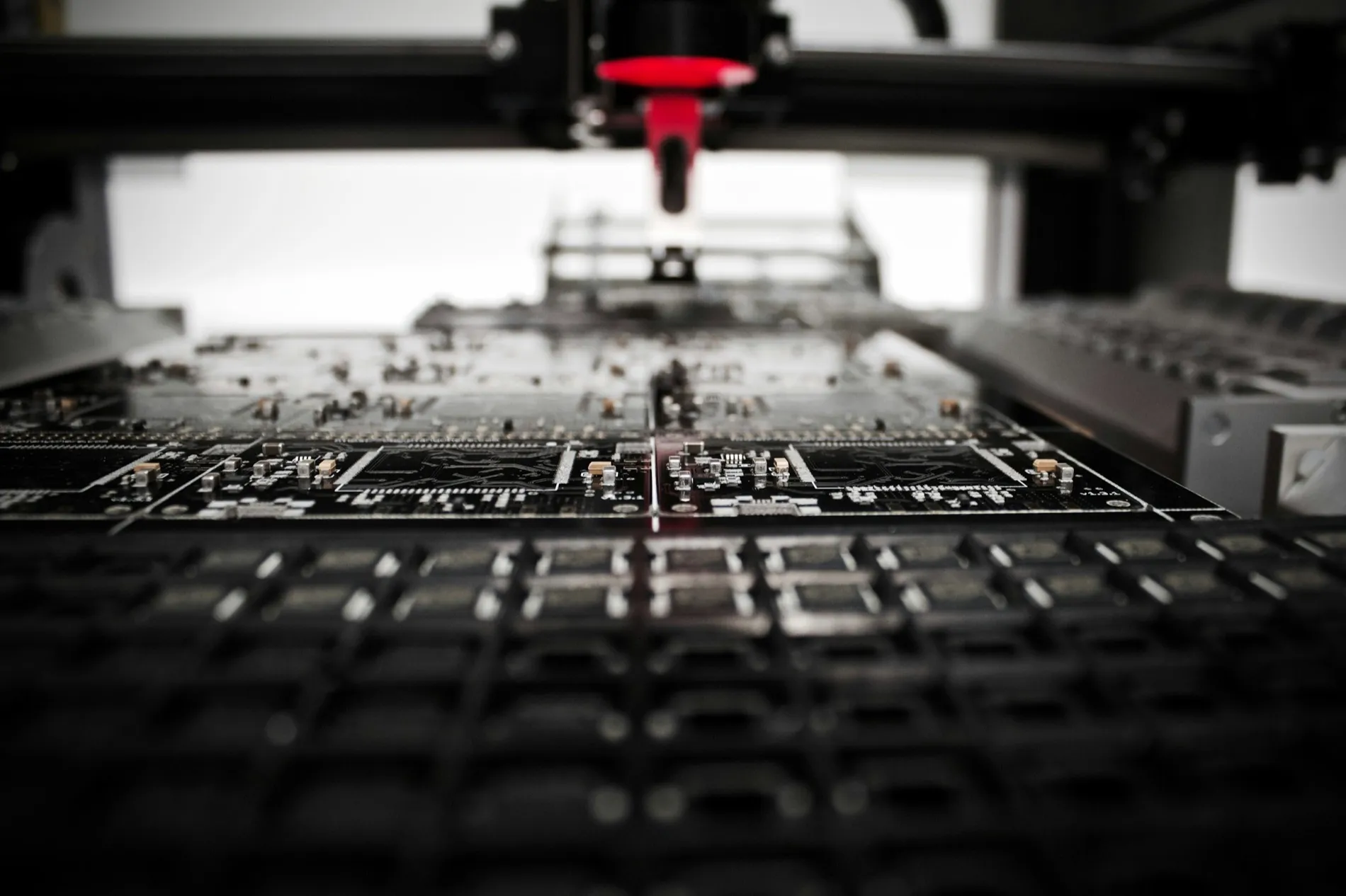 A pick-and-place head lowered over a dark circuit board