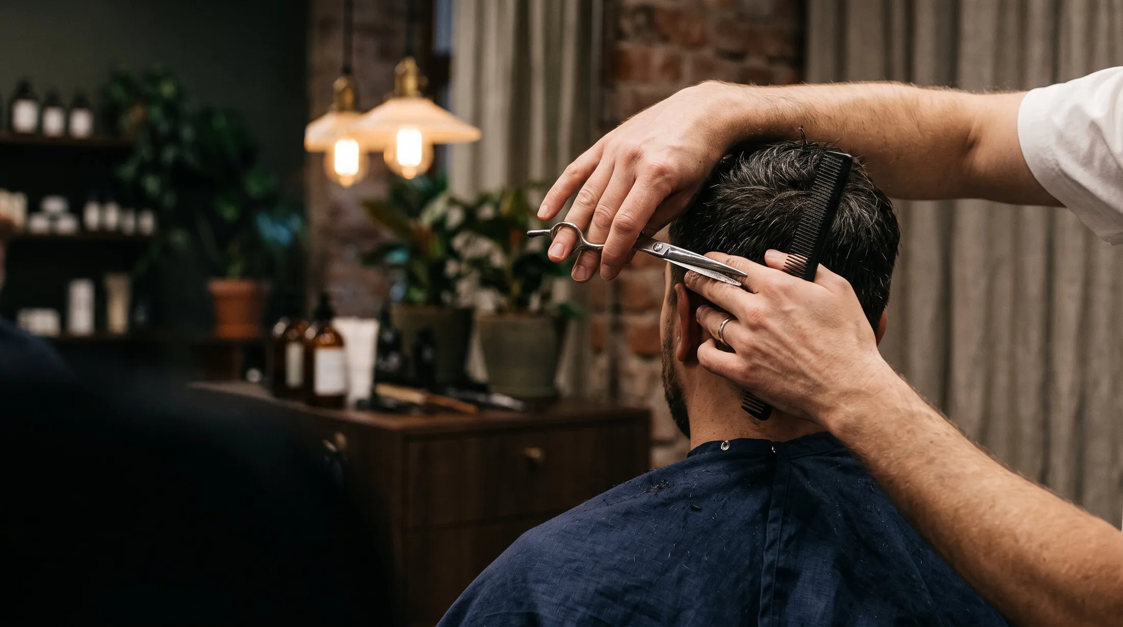 A barber mid cut, comb and scissors under a warm lamp